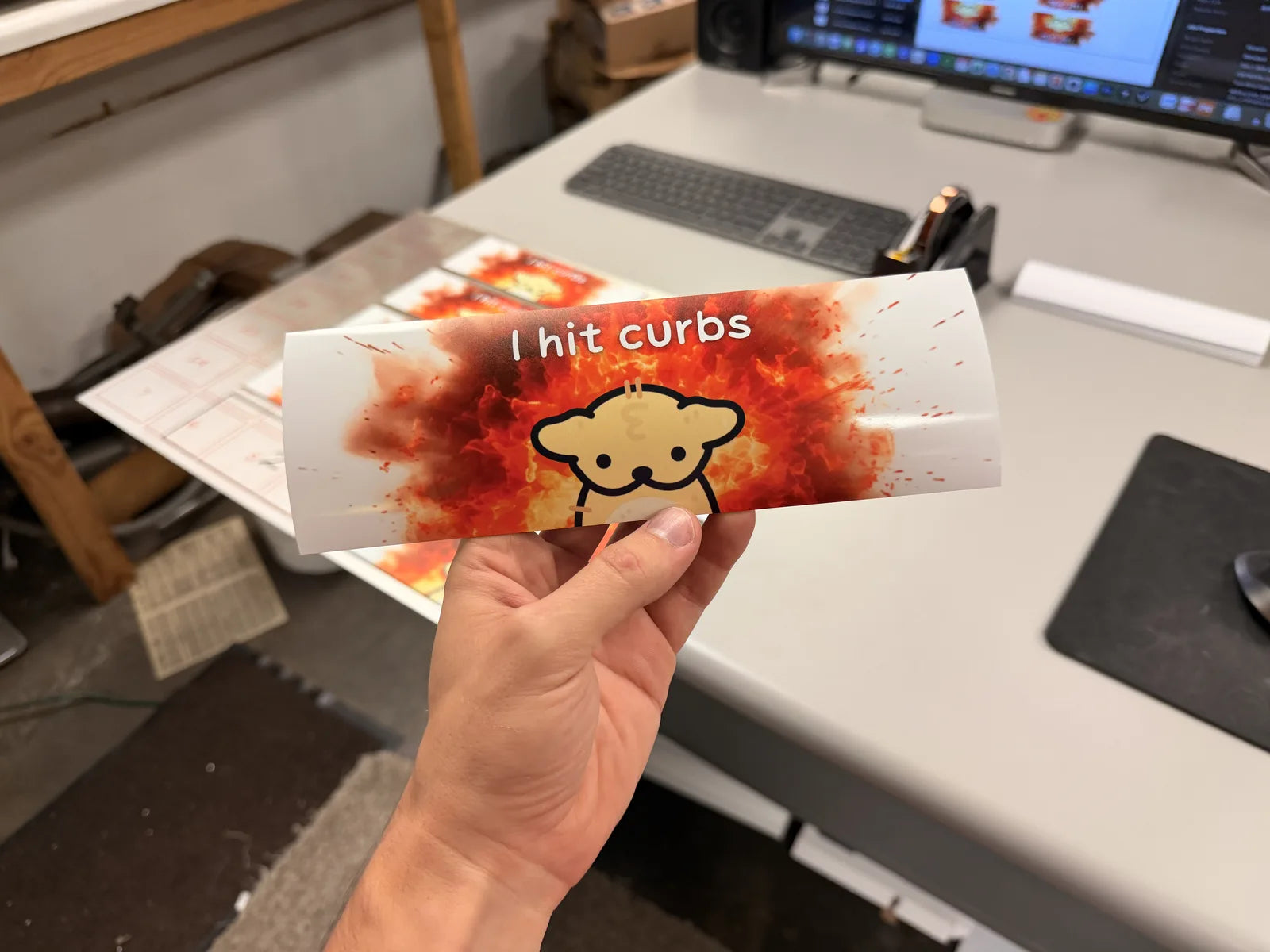Hand holding an eveoart Suni the Dog bumper magnet that reads I hit curbs, printed by Ti Project