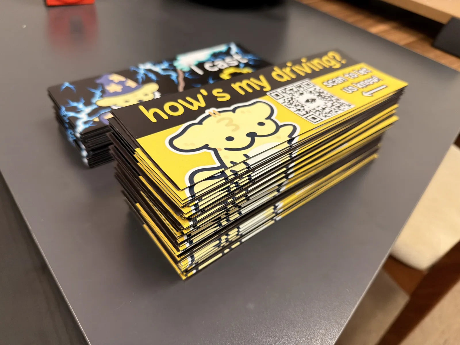 Stack of eveoart Suni the Dog bumper magnets that read how's my driving, printed by Ti Project